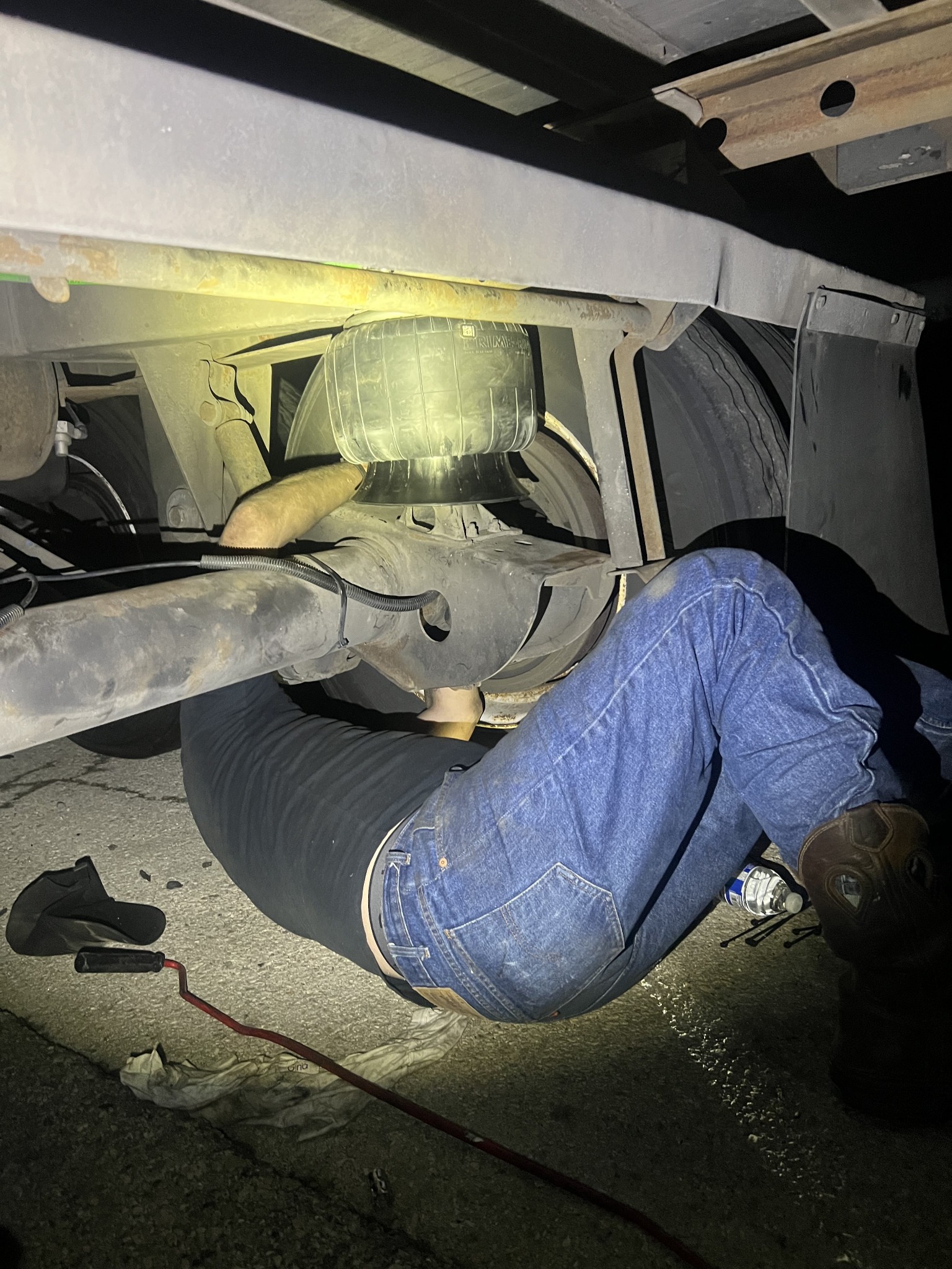 Technician working beneath a vehicle during a nighttime repair